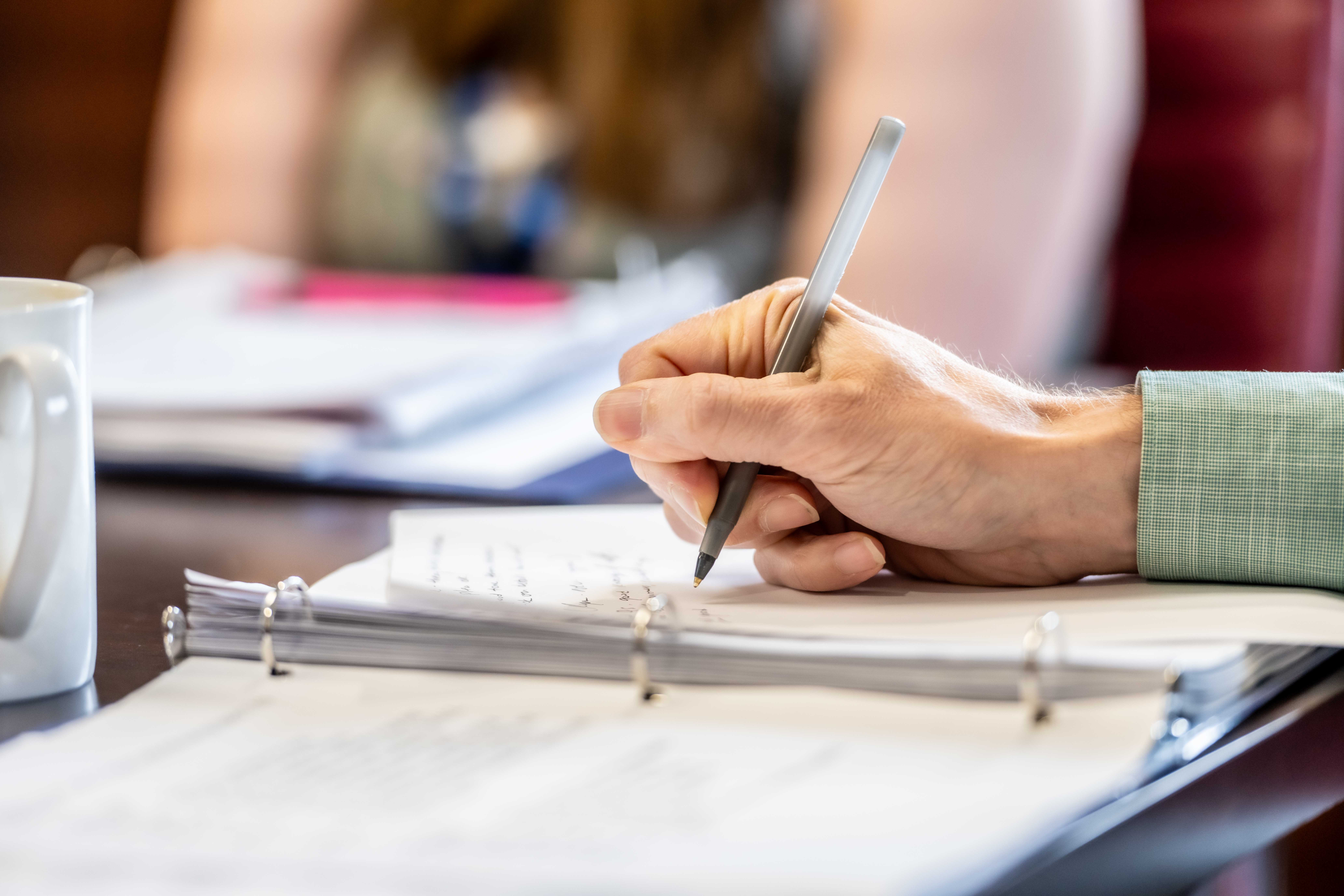 A hand holding a pen writing in a notebook