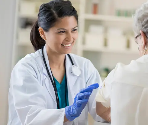 a women wearing scrubs helping an old lady get