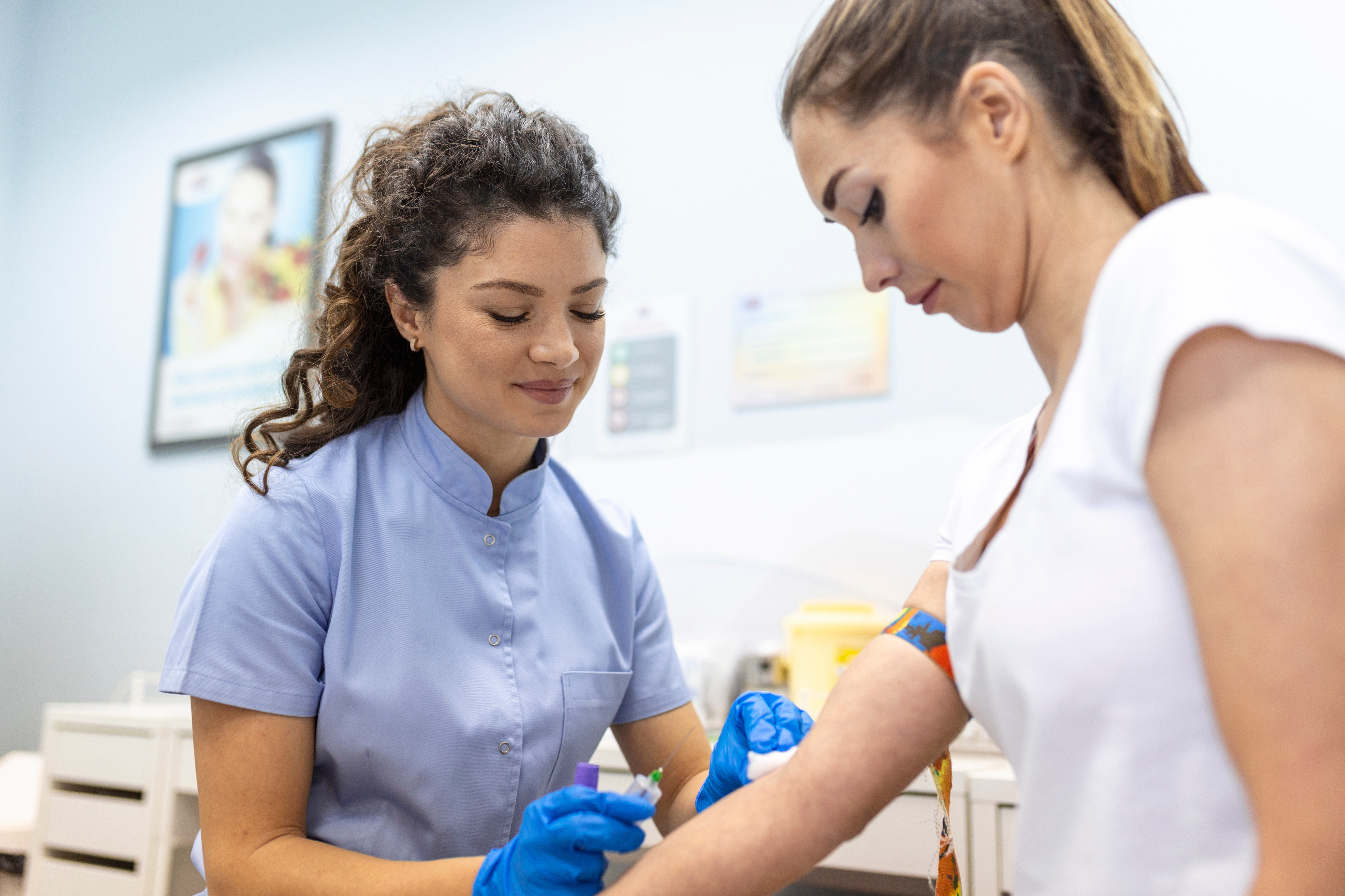 a women wearing labcoat prepping a man for getting blood drawn.